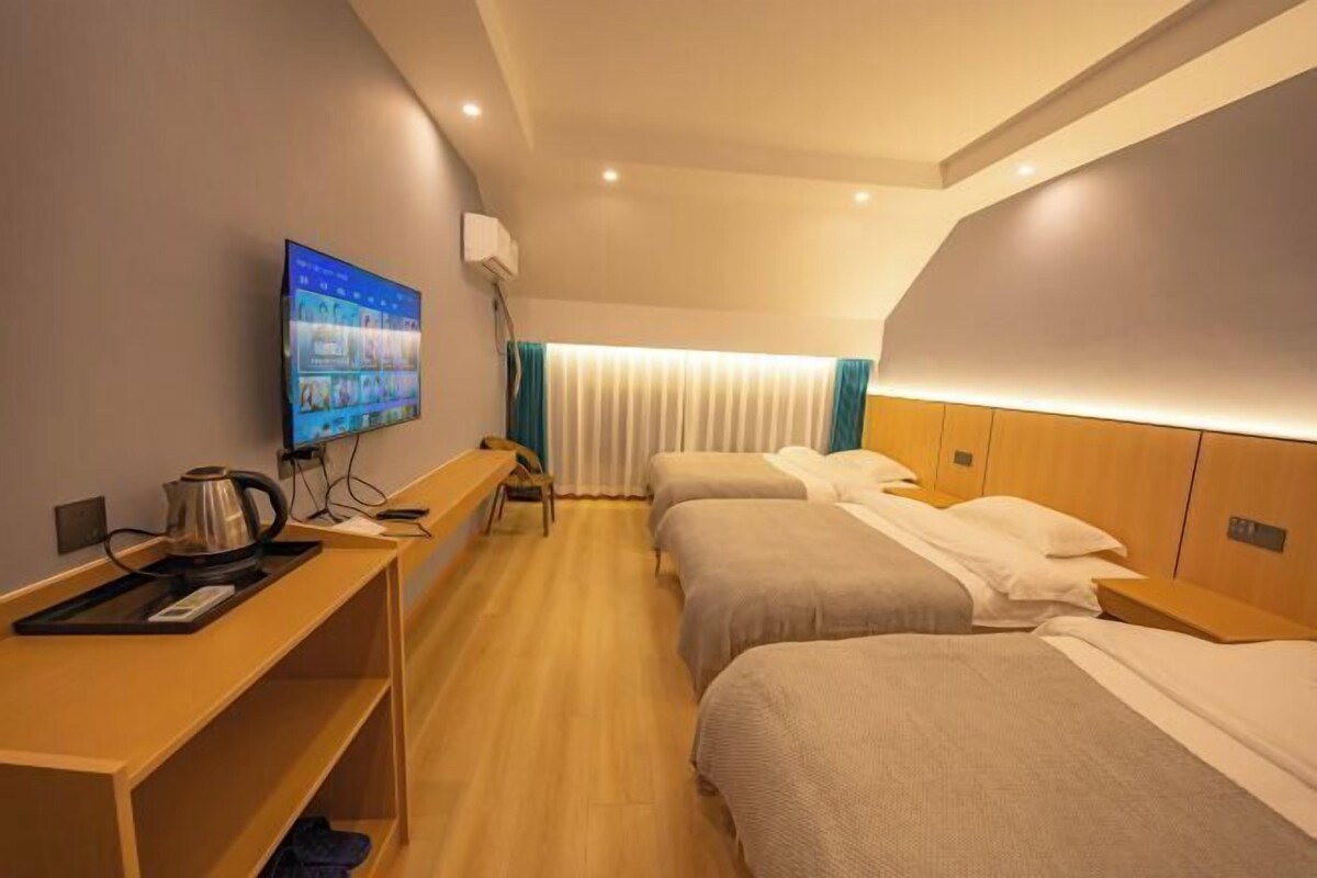 Ein Hotelzimmer mit zwei Betten, einem Schreibtisch mit Kaffeemaschine, einem Fernseher und einem Fenster mit Vorhängen.