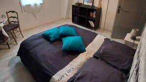 A bedroom with a bed, a chair, a desk, and a window.