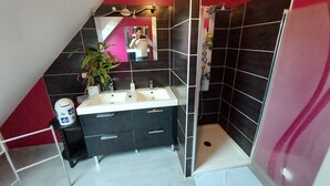 A modern bathroom with a dual sink vanity, a shower, and a large mirror.