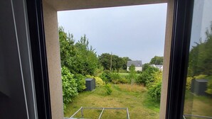 A window with a view of a garden and a building in the distance.