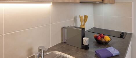 A modern kitchen with a stainless steel sink, a microwave, and a fruit bowl on the counter.