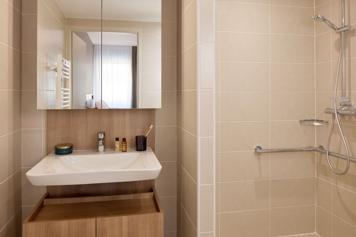 A bathroom with a white sink, mirror, and shower.