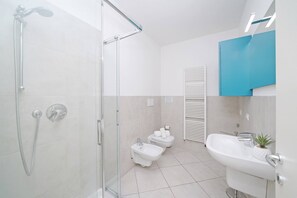 A modern bathroom with a glass-enclosed shower, a bidet, a sink, and a toilet. - Corte Fasanella appartamento Lillà (Toscolano-Maderno)