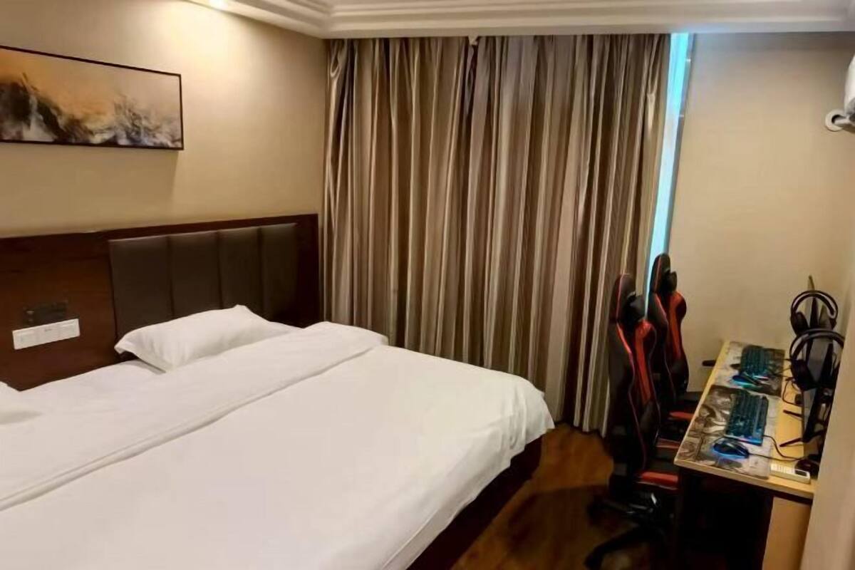 Une chambre d’hôtel avec un lit, un bureau avec un ordinateur et une chaise.