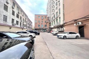 Un estacionamiento con coches aparcados en filas, rodeado de edificios de varios pisos con unidades de aire acondicionado.