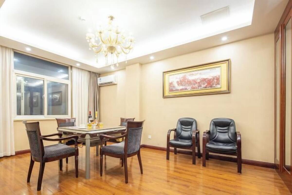 Un coin repas agrémenté d’un lustre, d’une table avec des chaises et d’un tableau encadré au mur.