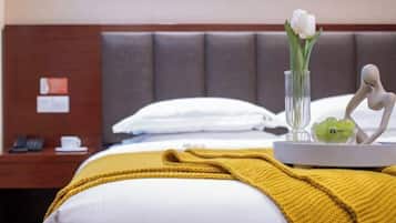 Ein Hotelzimmer mit einem Bett, einem Nachttisch mit Telefon, einer Vase mit Blumen und einem dekorativen Gegenstand auf dem Tisch.