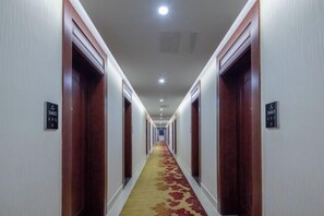 A hotel hallway with wooden doors, numbered room signs, and a carpeted floor. - Forever Star Hotel (Fuyang)