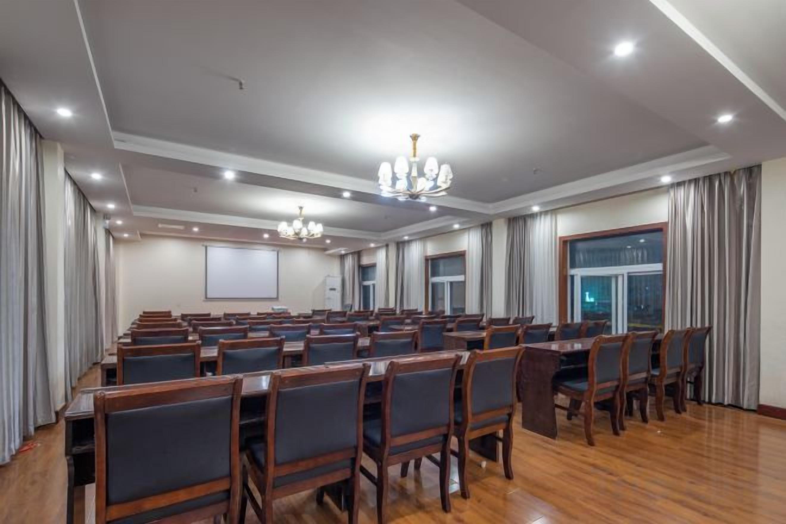 A conference room with rows of chairs, a large table, and a projector screen.