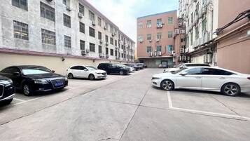 Un estacionamiento con varios autos estacionados frente a un edificio de fachada de ladrillo rojo.