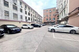 A parking lot with multiple cars parked in front of a building with a red brick facade.