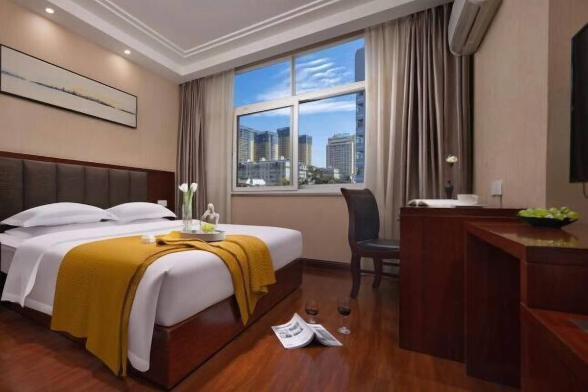 Une chambre d’hôtel avec un grand lit, un bureau et une fenêtre donnant sur la ville.