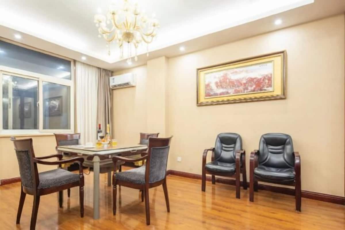 Un coin repas agrémenté d’un lustre, d’une table avec des chaises et d’un tableau encadré au mur.