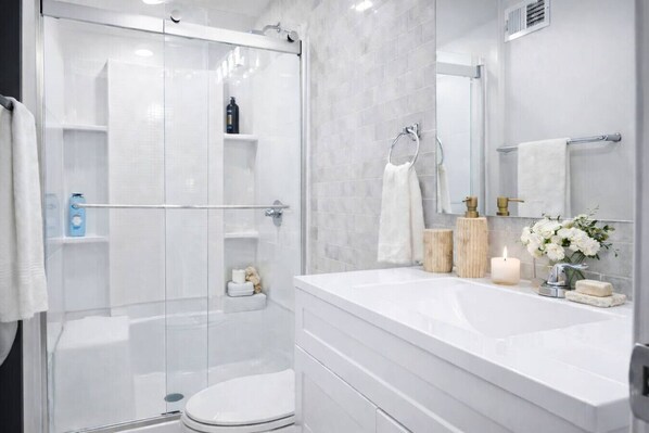 Een moderne badkamer met een douchecabine van glas, een wit toilet en een wastafel met spiegel.