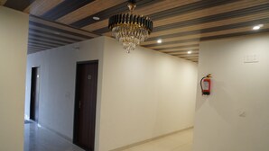 A hallway with a chandelier, a door, and a fire extinguisher on the wall. - Hotel Rajhans (Danta Ramgarh)