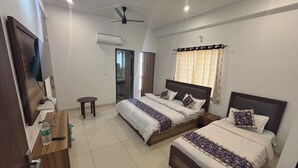 A hotel room with two beds, a TV, a ceiling fan, and an air conditioning unit. - Hotel Rajhans (Danta Ramgarh)