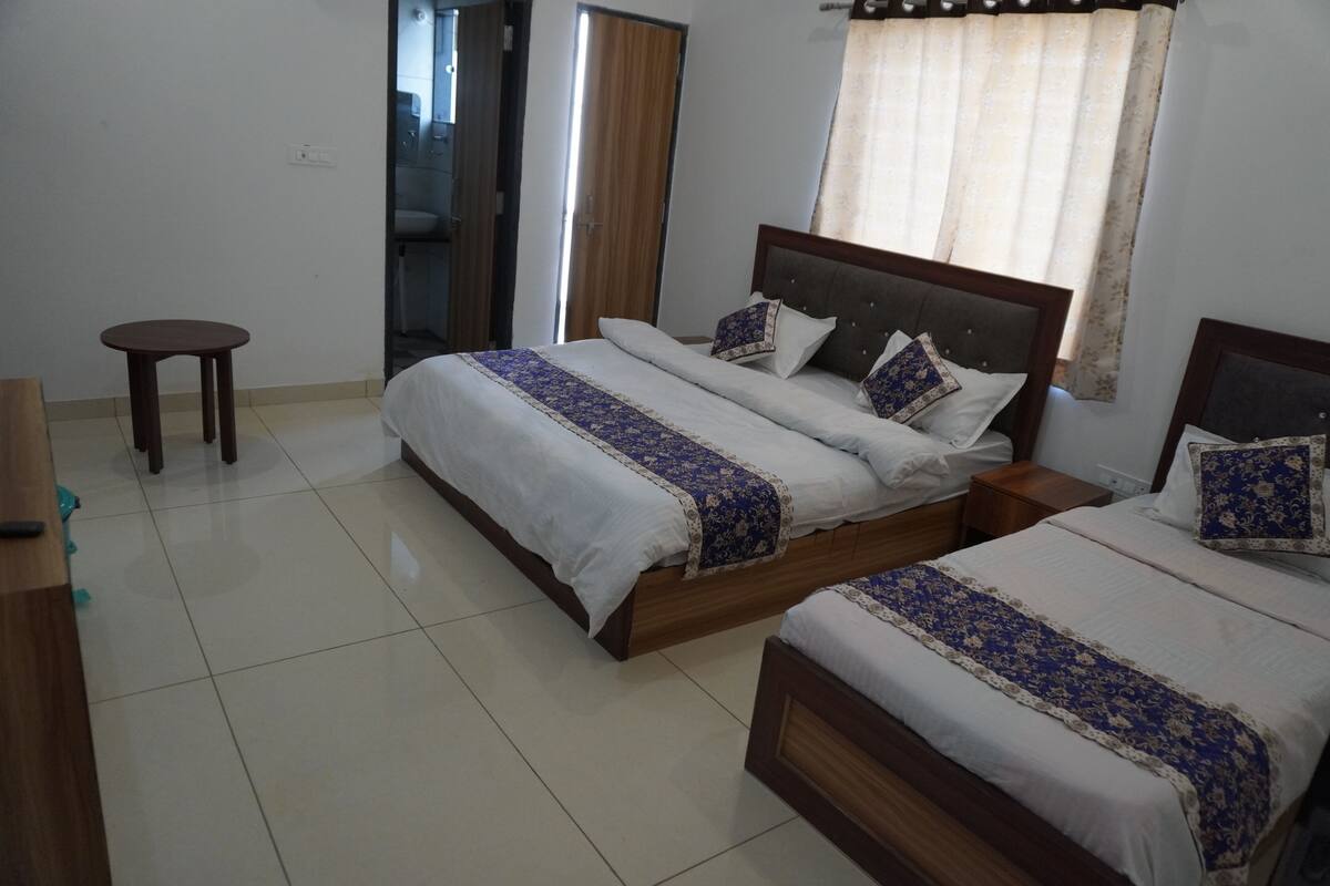 Una habitación de hotel con dos camas, una mesita redonda pequeña y una mesita de noche de madera.