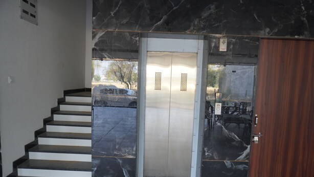 A marble staircase leading to an elevator with a wooden door. - Hotel Rajhans (Danta Ramgarh)