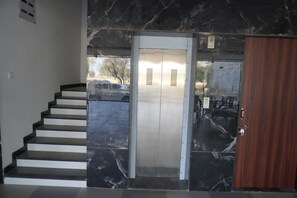 A marble staircase leading to an elevator with a wooden door.