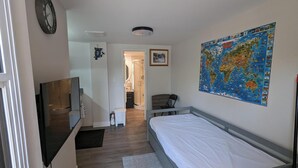 A bedroom with a bed, a TV, a map on the wall, and a shower area.