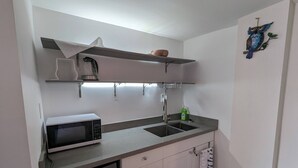A compact kitchen with a microwave, sink, and storage cabinets.