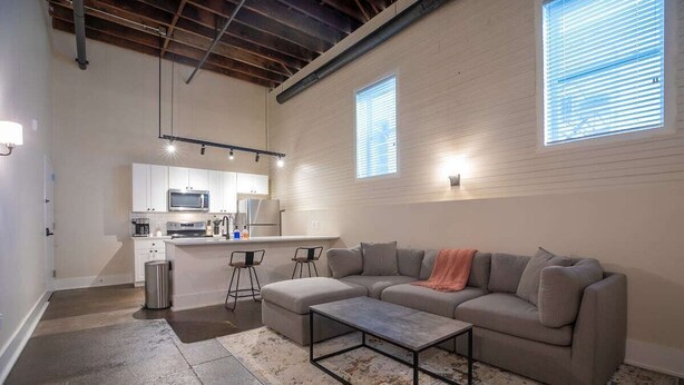 Una sala moderna con un sofá modular, una mesa de centro y una cocina al fondo.