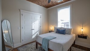 Una camera da letto con un letto, comodini, una ventola a soffitto, una finestra e una porta.