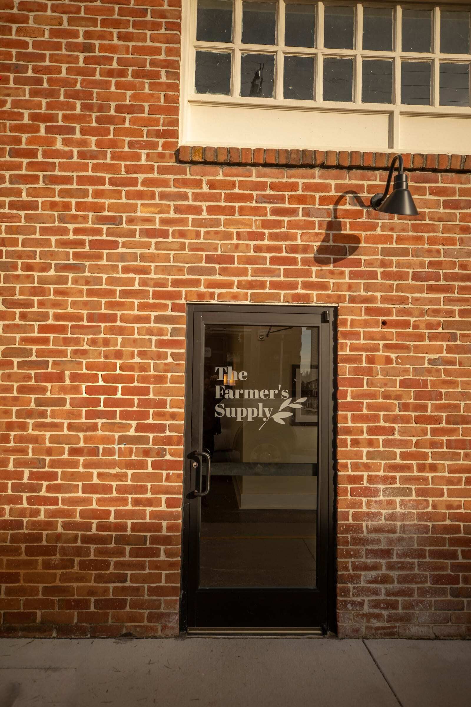 A brick building with a glass door labeled "The Farmer's Supply".