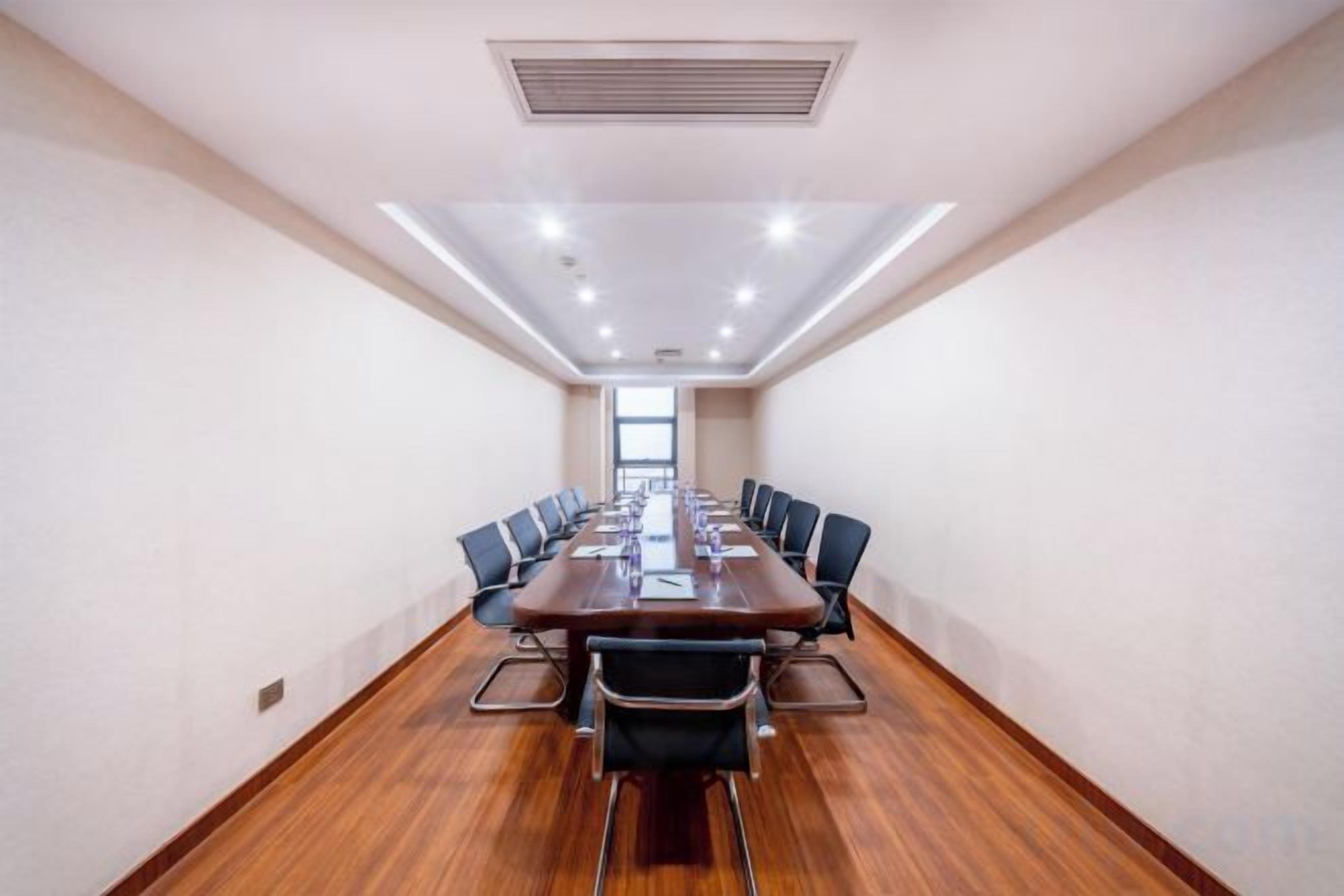 A conference room with a long table, chairs, and a ceiling vent.