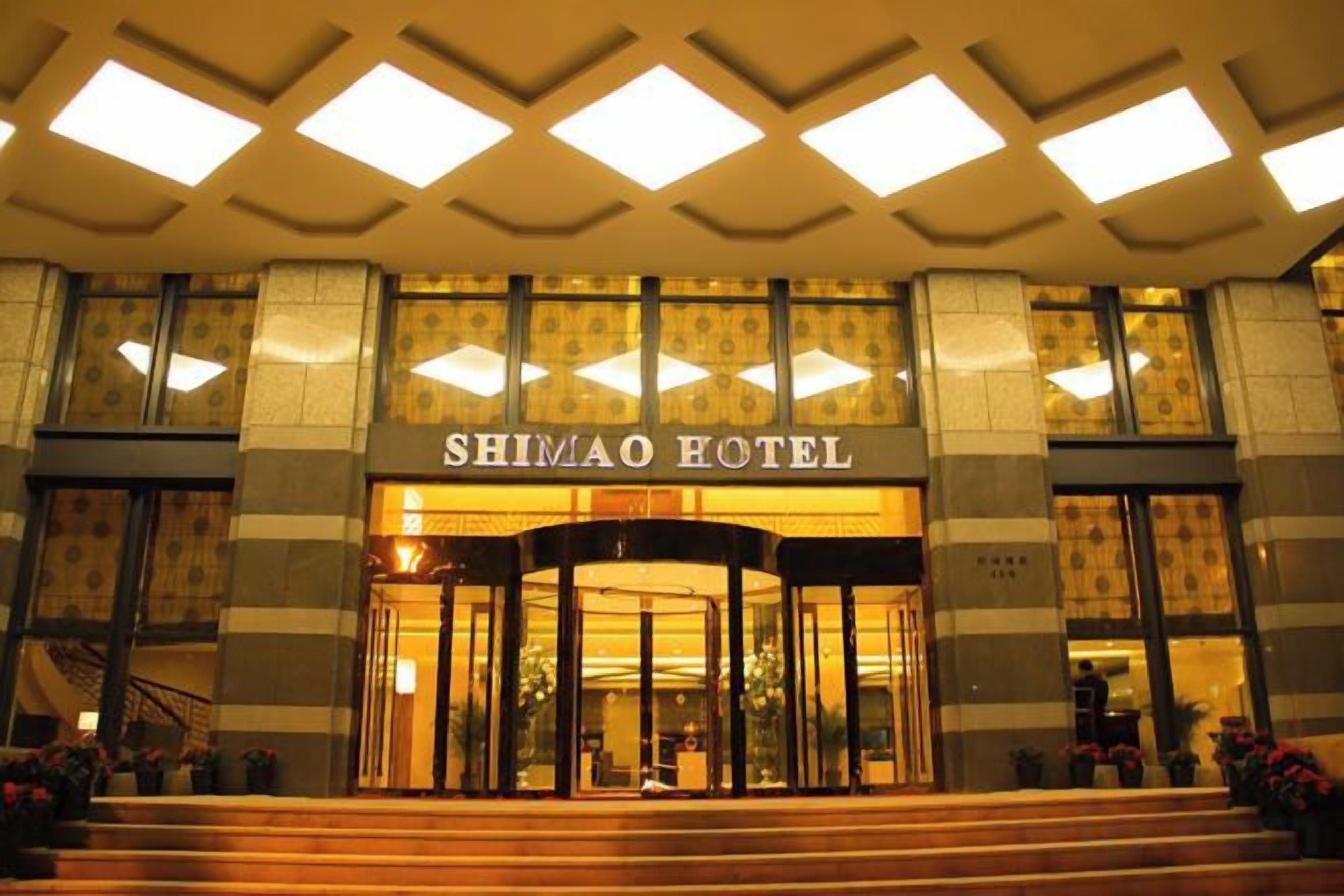 The entrance of the Shimao Hotel with a grand facade, large windows, and a central entrance.
