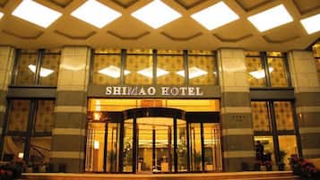 The entrance of the Shimao Hotel with a grand facade, large windows, and a central entrance.