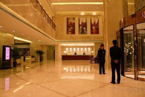 A hotel lobby with a reception desk, a staircase, and a large window. - Shimao Hotel (Zhoushan)