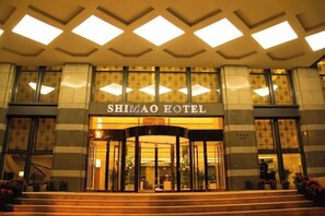 The entrance of the Shimao Hotel with a central revolving door and a tiled facade. - Shimao Hotel (Zhoushan)