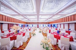 A banquet hall with rows of tables, white tablecloths, and red centerpieces. - Shimao Hotel (Zhoushan)