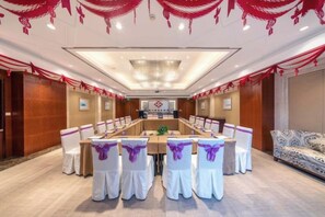 A conference room with a long table, white chairs with purple sashes, and red drapes on the ceiling. - Shimao Hotel (Zhoushan)