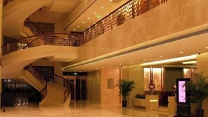 Eine geräumige Lobby mit einer imposanten Treppe, einem Empfangsbereich und einem modernen Design.