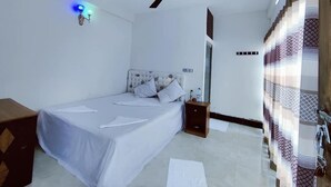 A bedroom with a bed, a nightstand, a ceiling fan, and a wall-mounted light fixture. - Hotel Royal Beach & Restaurant (Saint Martin's Island)