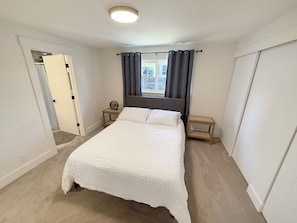 A bedroom with a large bed, two bedside tables, a ceiling light, and a view of the outside through a window with curtains. - Spacious 4BR Upper Duplex Unit • AC • WiFi • Quiet Area • Near SeaTac Airport (SeaTac)