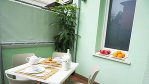 A dining area with a table set for two, a plant, and a window with fruit. - Four-room apartment Scola 01 (Gabicce Mare)