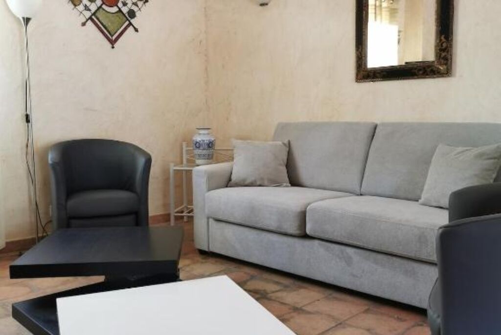 Een woonkamer met een grijze bank, een zwarte fauteuil, een bijzettafeltje en een vloerlamp.