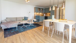 A modern living room with a sofa, coffee table, and dining area with chairs. - Slow Down - Loggia. Sauna. Beach chair included. Close to the Baltic Sea. (Kellenhusen)