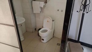 Ein kleines Badezimmer mit zwei Toiletten, einem weißen Waschbecken und einem Handtuchhalter.