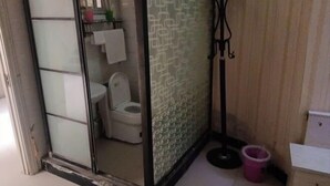 Ein Badezimmer mit Toilette, Glasabtrennung und Fußbodenablauf.