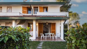 Une maison à deux étages dotée d’un patio couvert, d’un coin repas et d’un petit jardin.