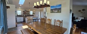 A spacious dining area with a wooden table and chairs, a kitchen in the background, and a mountain view painting on the wall. - New Listing! Granite Heights in Custer State Park (Custer)