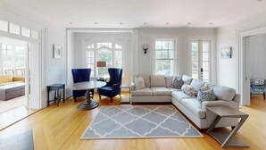 A spacious living room with a large sectional sofa, a round coffee table, and a blue armchair.
