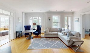 A spacious living room with a large sectional sofa, a round coffee table, and a blue armchair.