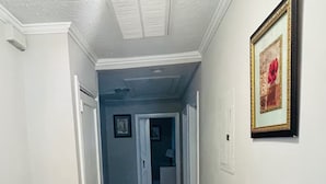 A hallway with dark wood flooring, white walls, and a framed picture on the right. - Rudolph home (Goldsboro)