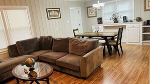 A living room with a brown sectional sofa, a glass coffee table with a globe, and a dining area with a wooden table and chairs. - Rudolph home (Goldsboro)