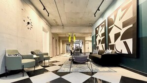 A modern lobby with a checkered floor, a sofa, armchairs, a coffee table, and abstract wall art. - C Living 2 - Executive - 1BD Apartment City View (Riyadh)